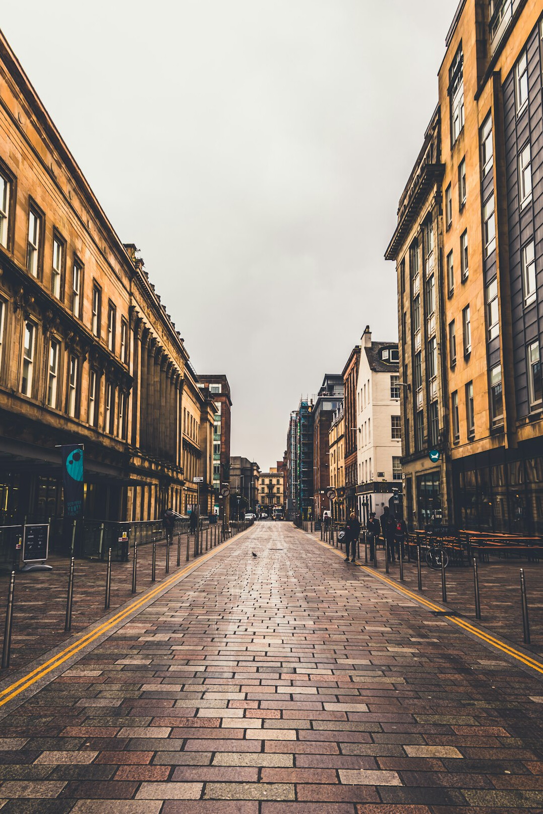 Narrow city street lined with old brick buildings and pedestrians