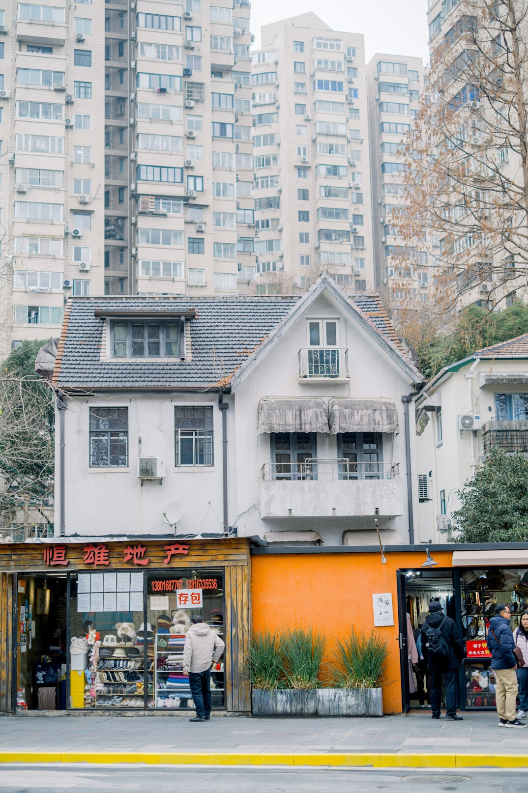 People standing in an outdoor queue outside a small city shop